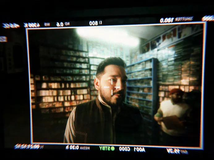 Behind the scenes on set, a presenter framed on a camera monitor